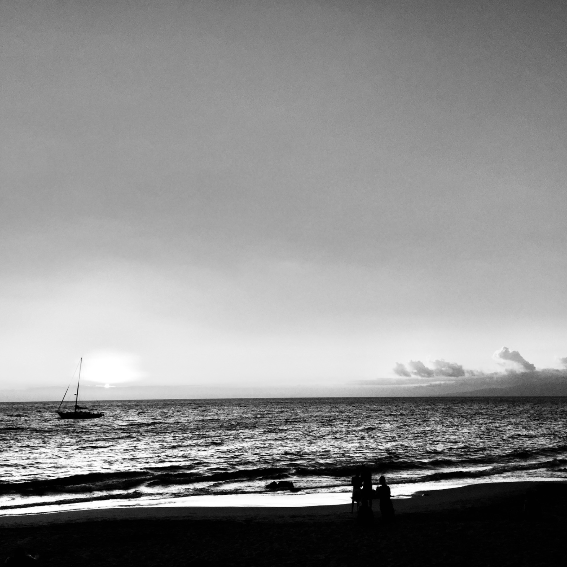 A lone sailboat off the Oregon coast at dusk, in black and white